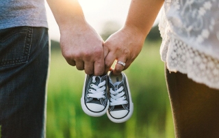 Man and Woman Holding Baby Shoes in Hands